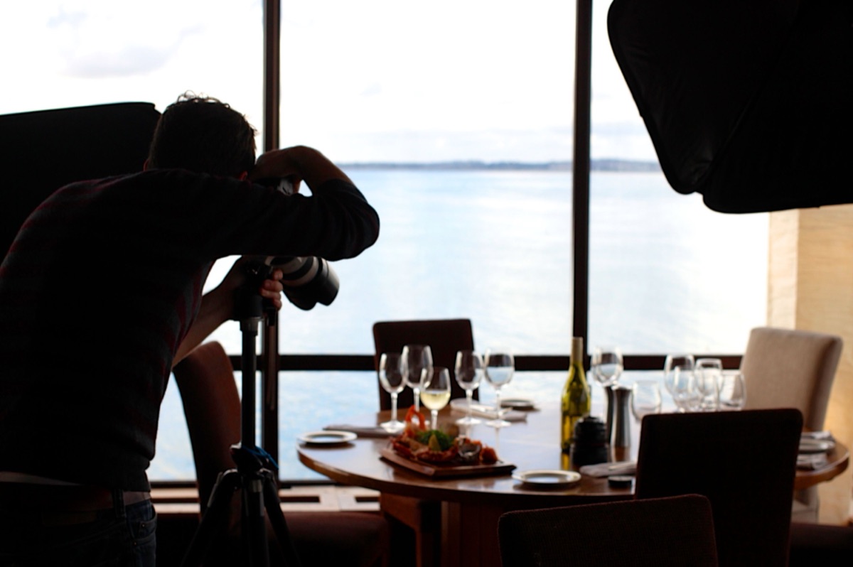 Un photographe photographie un plat sur une table de restaurant